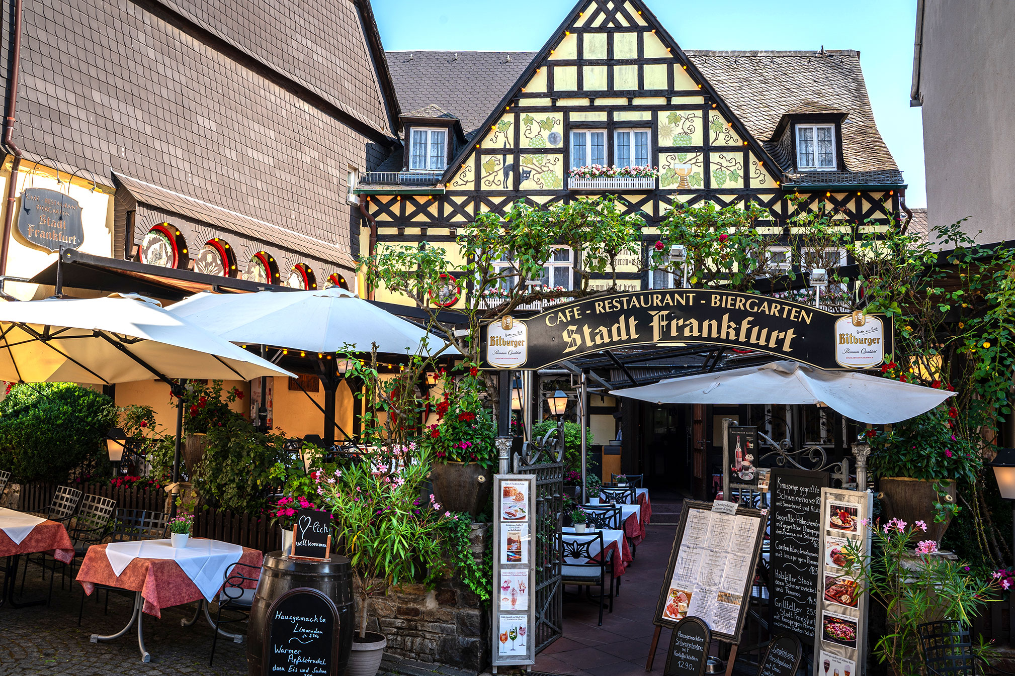 Eingang des Restaurants Stadt Frankfurt mit Fachwerkfassade, Biergartenschild und dekorierten Außentischen