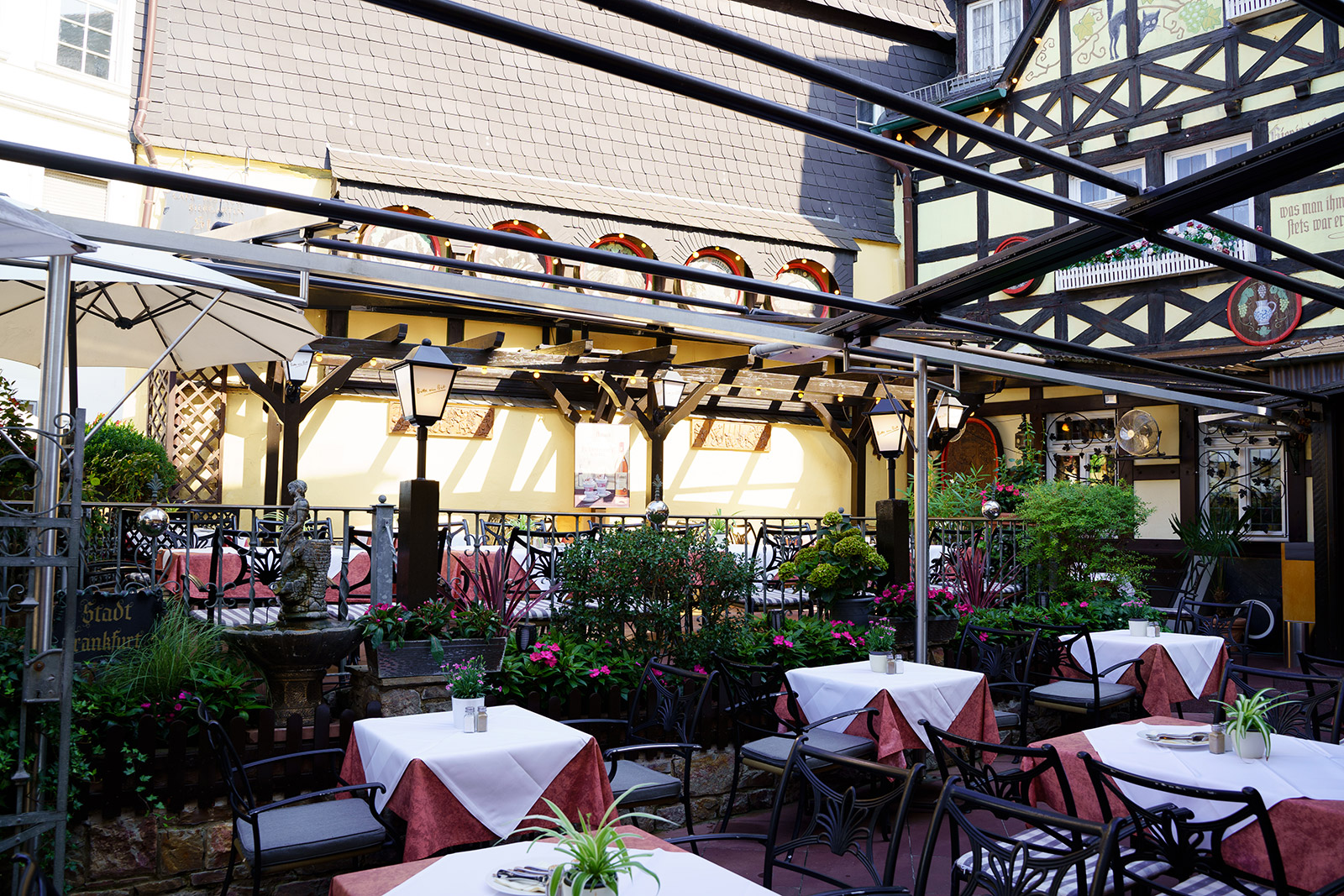 Terrassenblick mit Blumen, Fachwerkfassade und überdachten Sitzplätzen