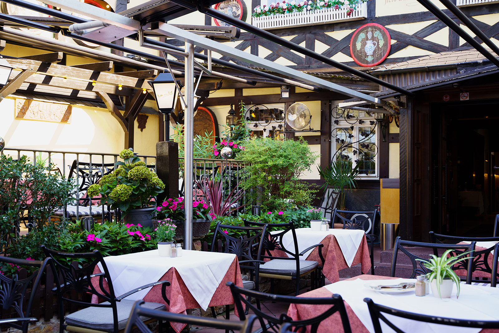 Nahansicht der Terrasse mit bunten Blumen und geöffnetem Eingang zum Restaurant