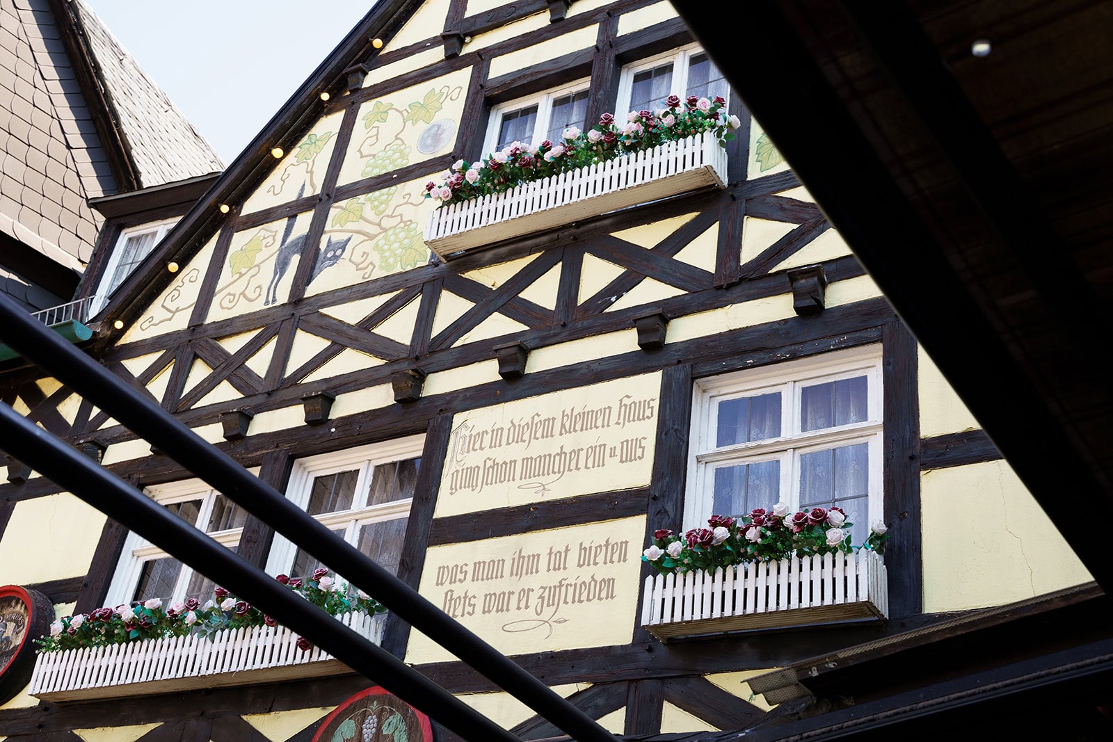 Schräger Blick auf die Fachwerkfassade mit Blumenkästen und Inschrift
