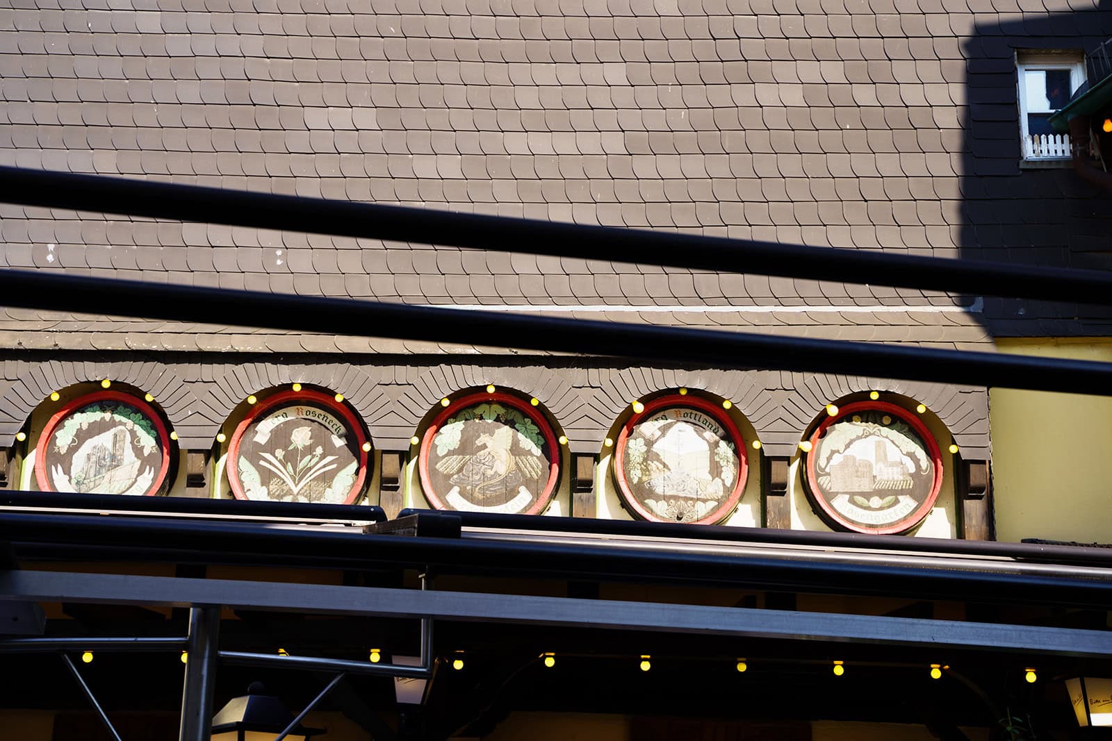 Fünf bemalte Weinfassdeckel an der Hausfassade des Restaurants