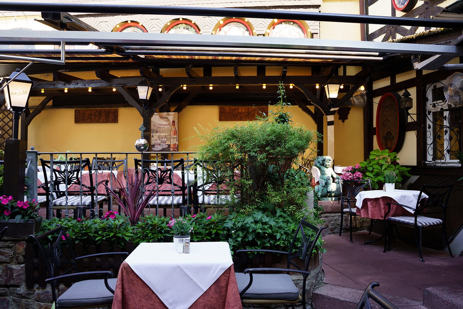 Pflanzen, Sitzplätze und Statue auf der Restaurantterrasse